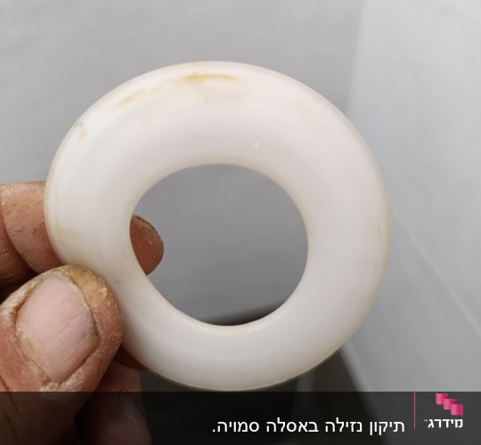 טבעת פלסטיק לבנה מוחזקת ביד מלוכלכת